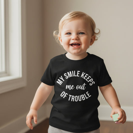 Infant Tee — “My Smile Keeps Me Out of Trouble” Funny Baby Graphic Shirt